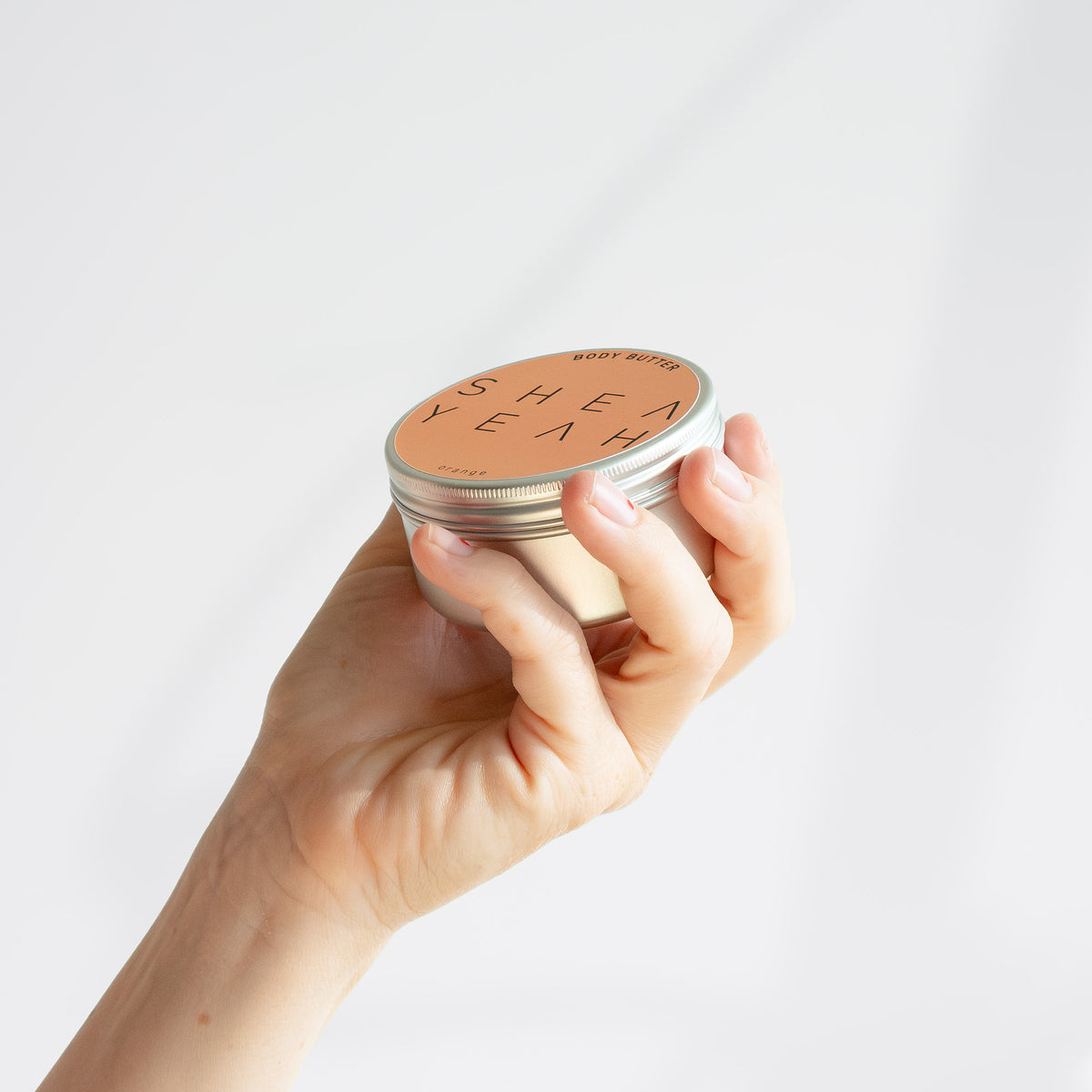 Shea Yeah Body Butter mit Orangenduft in der Hand gehalten.
